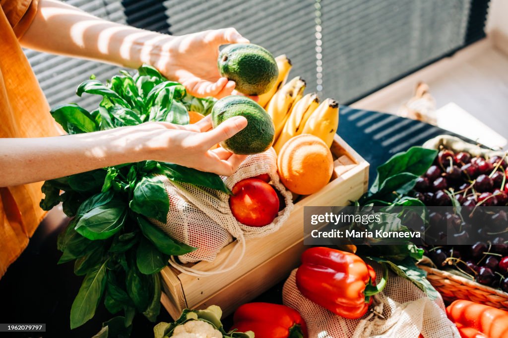 A woman unpacks fruits and vegetables at home after shopping at a local farmers' market.