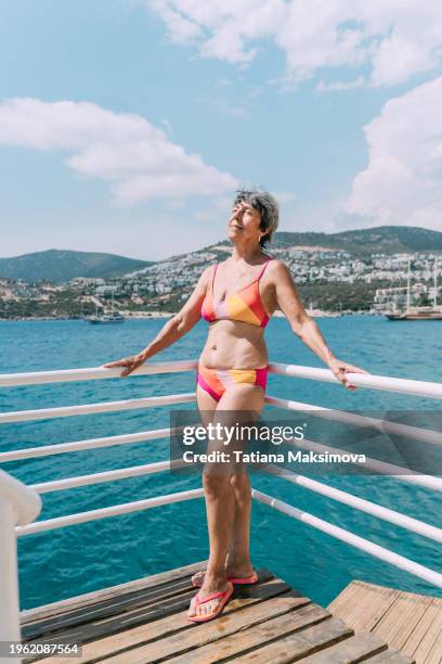 a woman of retirement age on the turquoise sea background. trampolines in the background. - mediterranean turkey stock pictures, royalty-free photos & images