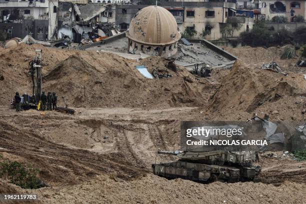 This picture taken during a media tour organised by the Israeli military on January 27 shows an Israeli army tank rolling past the damaged Hamza...