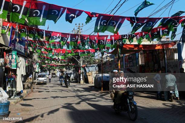 Commuters move past the election banners and posters of Pakistan People's Party hung over a street in Karachi on January 29 ahead of the upcoming...