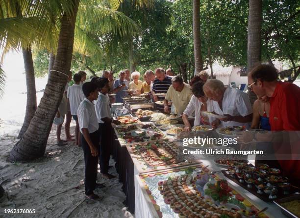 Tourists at the buffet under palm trees on January 27, 2024 on Baros, Maldives. Tourism is the main source of income for the Maldives.