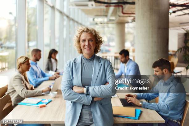 happy female ceo with crossed arms in the office. - mensen op de achtergrond stockfoto's en -beelden