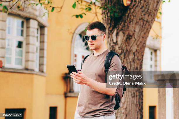 young man in the city checking cell phone - mitteleuropa stock-fotos und bilder