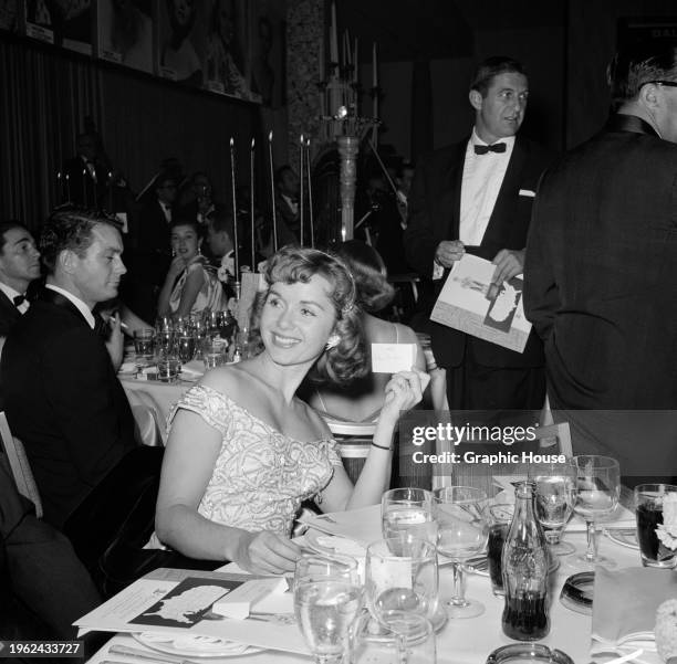 American actress and singer Debbie Reynolds, holding a piece of paper bearing the name of her husband 'Eddie Fisher' sitting at her table at the...