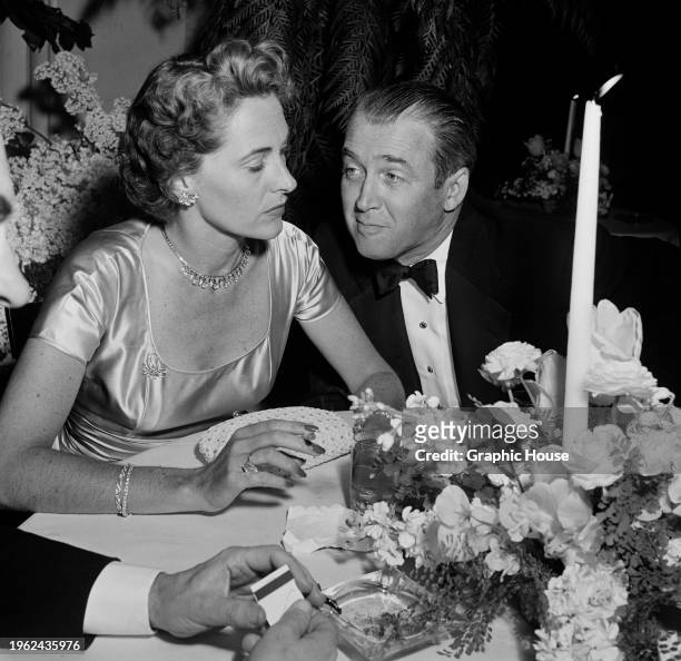 American actress and model Gloria Hatrick McLean, wearing a short-sleeved scoop neck outfit, and her husband, American actor James Stewart, who wears...