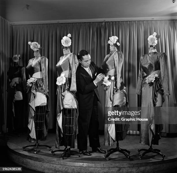 Broadway costume designer Billy Livingston among a group of dressmaker's dummies, making adjustments to one of his stage costumes, United States,...