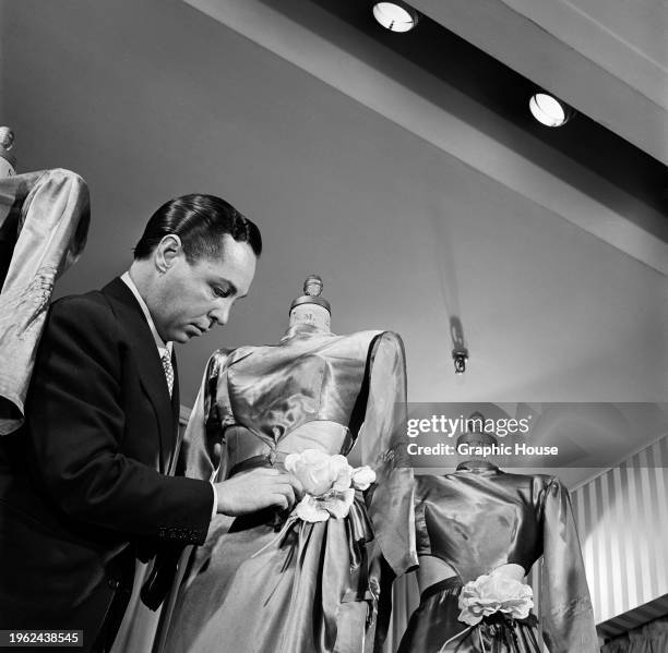 Broadway costume designer Billy Livingston making adjustments to one of his stage costumes on a dressmaker's dummy, United States, 30th June 1947.