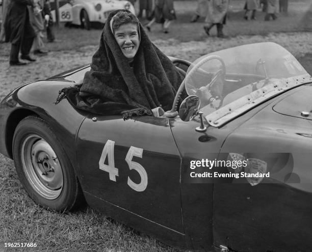 British racing driver Rosemary Seers seated in a racecar with a blanket draped over her head and shoulders, July 2nd 1957. Photo by Evening...