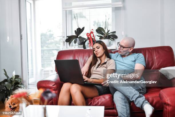 wife and husband choosing a movie to watch on laptop after husband's chemotherapy - shaved dog stock pictures, royalty-free photos & images