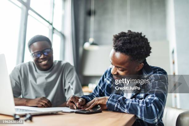 zwei junge erwachsene schwarze männliche studenten machen hausaufgaben mit einem laptop - male student wearing glasses with friends stock-fotos und bilder