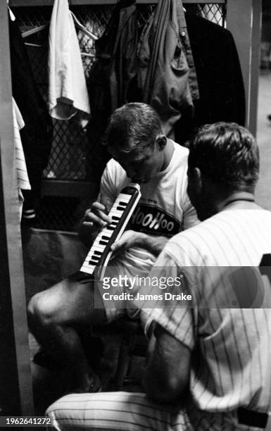 Mickey Mantle of the New York Yankees talks with Whitey Ford as he plays a melodica prior to a game against the Boston Red Sox at Yankee Stadium on...