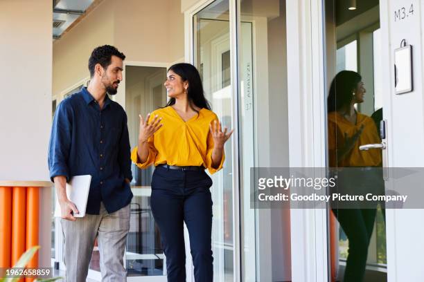 diverse businesspeople talking while walking down an office hallway - corporate modern office bright diverse imagens e fotografias de stock