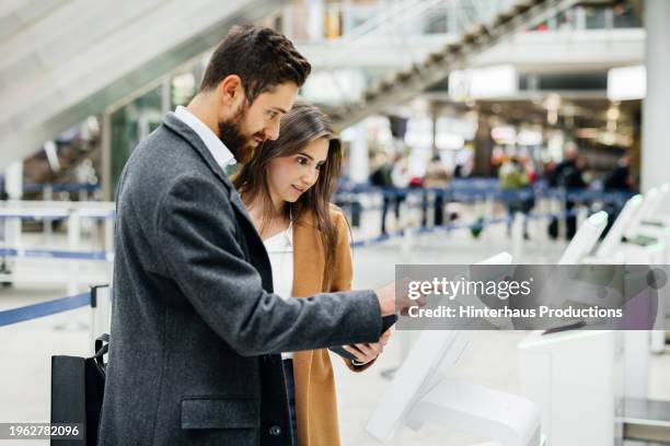 young travelers interacting with kiosk screen - libre service photos et images de collection