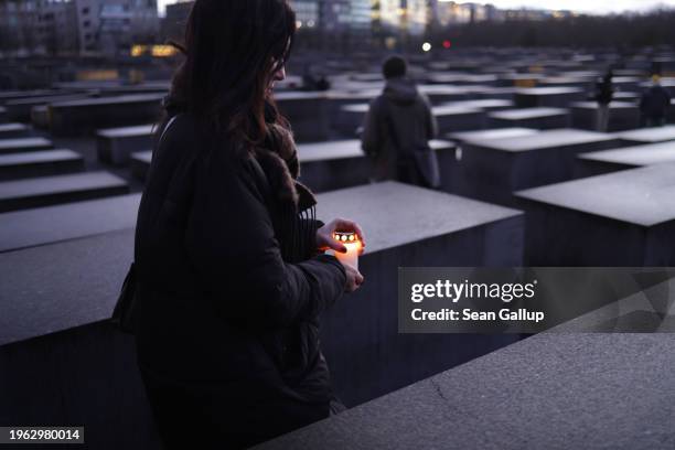 Local woman prepares to lay a candle among stelae at the Memorial to the Murdered Jews of Europe, also called the Holocaust Memorial, on the eve of...