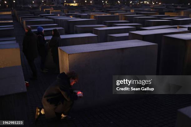 Young man lights a candle among stelae at the Memorial to the Murdered Jews of Europe, also called the Holocaust Memorial, on the eve of...