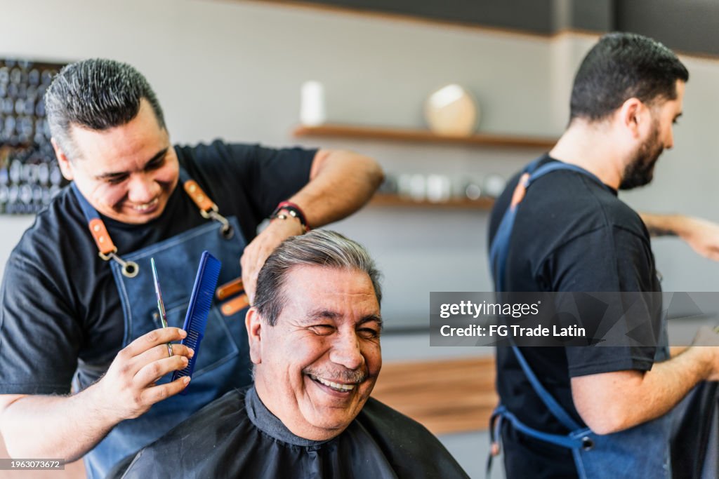 Barber cutting his customer hair at barber shop
