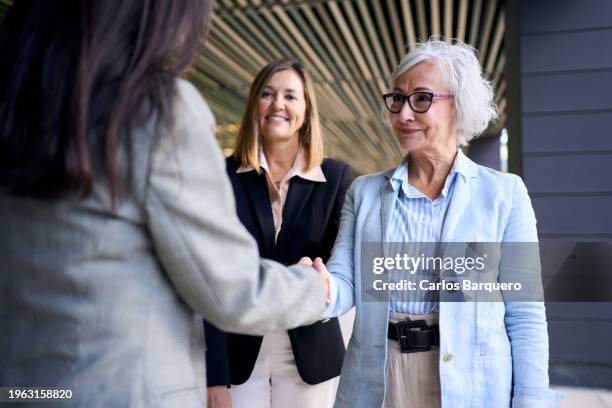 cheerful senior woman shaking hands with a female colleague to close a deal. - igualdad de género fotografías e imágenes de stock
