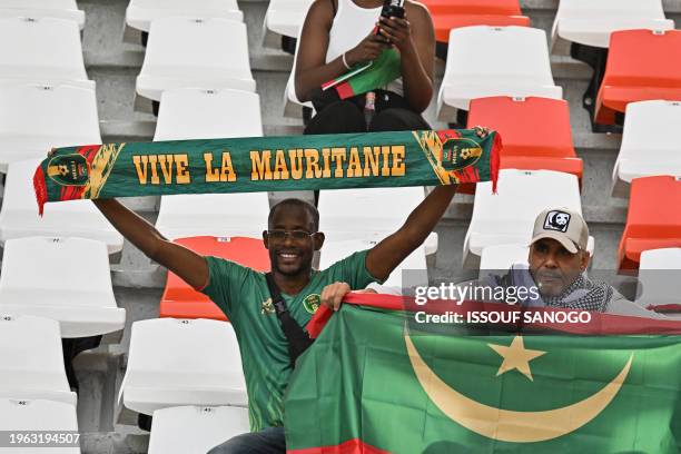 Mauritania's supporters hold a Mauritanian flag and a scarf ahead of the Africa Cup of Nations 2024 round of 16 football match between Cape Verde and...