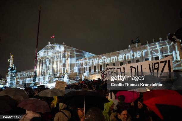 People hold up a sign reading "Austria you Nazi" as they gather in front of the Austrian Parliament to protest against right-wing extremism as...