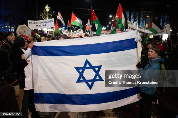 People hold up a flag of Israel in front of Pro-Palestinian demonstrators who joined people gathering in front of the Austrian Parliament to protest...