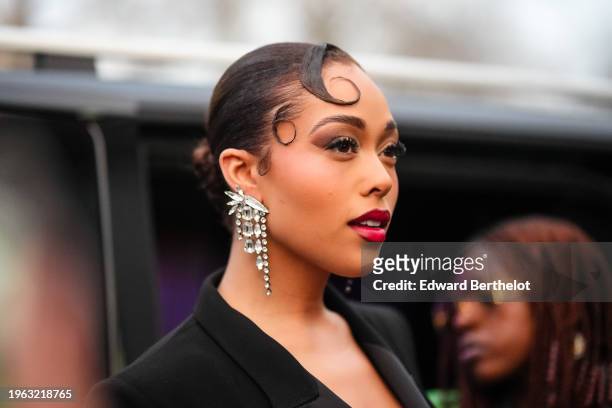 Jordyn Woods wears bejeweled earrings, red lipstick, a black blazer jacket, outside Zuhair Murad, during the Haute Couture Spring/Summer 2024 as part...