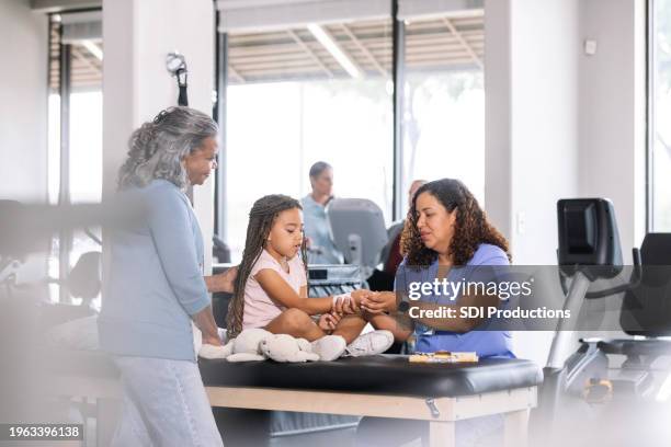 female ot carefully touches young girl's injured wrist - injured nurse stock pictures, royalty-free photos & images