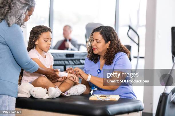 grandmother and elementary age girl show therapist injured wrist - injured nurse stock pictures, royalty-free photos & images