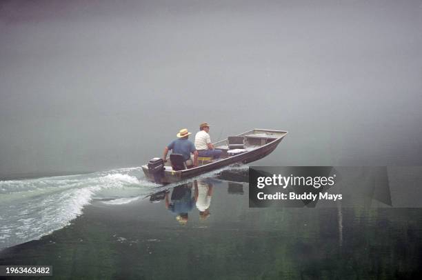 Fishermen set out in their boat in search of bass and crappie on a misty morning on Lake Conway, Arkansas, in the Ozark Mountains, 1996. .