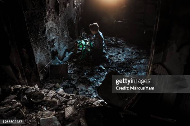 Hamzeh El Sabbagh, 5 tries to recover and play with his charred tricycle inside his home that was completely burned after Israeli forces destroyed...