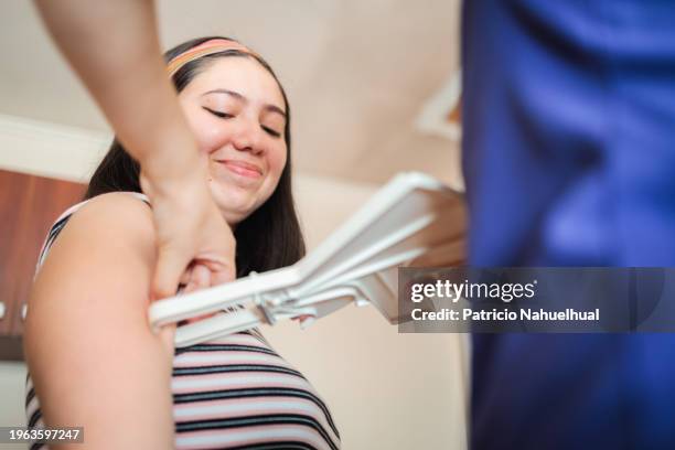 home visitor latin female nutritionist measuring skin fold thickness, subcutaneous body fat with a caliper, from a young patient's arm - skin fold calliper ストックフォトと画像