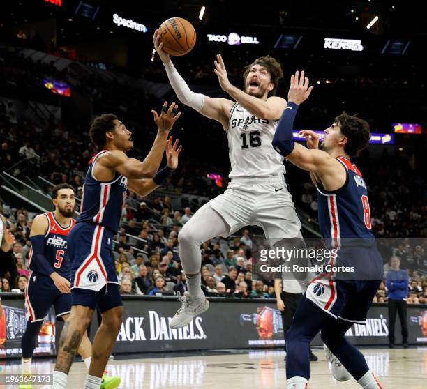 Cedi Osman of the San Antonio Spurs drives on Deni Avdija and Jordan Poole of the Washington Wizards in the first half at Frost Bank Center on...