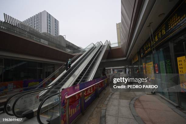 People use an escalator in a partially operating Evergrande commercial complex in Beijing on January 30, 2024. A Hong Kong court on January 29...