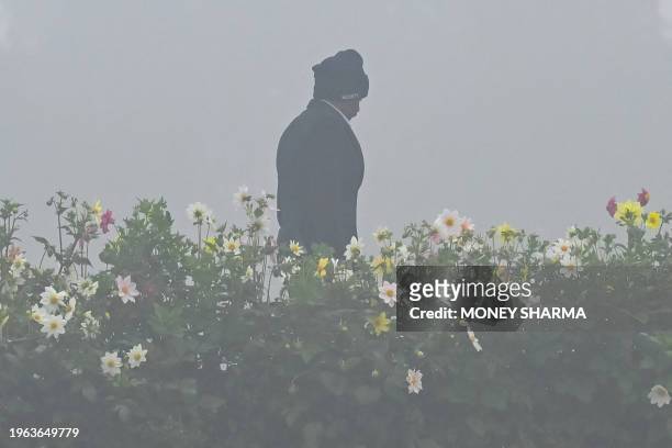 Security personnel walks amid dense fog at the Mahatma Gandhi memorial at Rajghat on Gandhi's death anniversary in New Delhi on January 30, 2024. The...