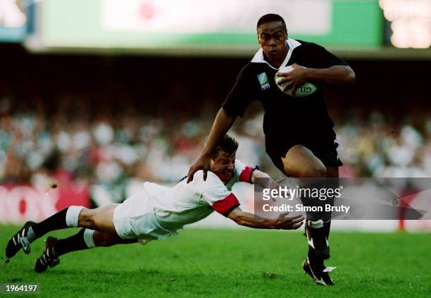 Jonah Lomu of New Zealand evades a challenge from Rob Andrew of England during the Rugby World Cup semi final between England and New Zealand on June...