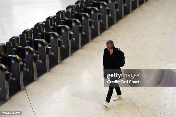 Man talks on his phone next to ticket barriers in Waterloo Railway Station during a strike by members of the Associated Society of Locomotive...