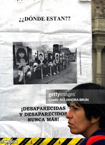 Pedestrian passes by a poster against political violence during a demonstration in front of the Government Palace in Lima, Peru, 25 May 2001. The...