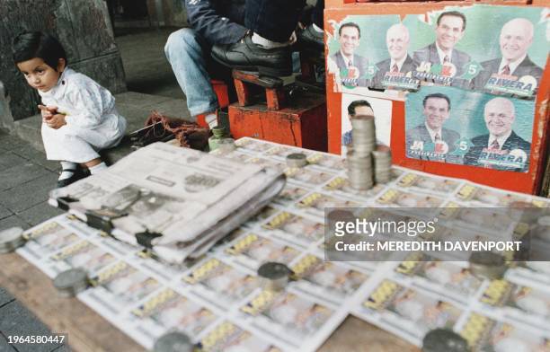 Child sits next to election propoganda in downtown Quito, Ecuador, 10 July. Popular Democracy Party candidate Jamil Mahuad is favored to win over...