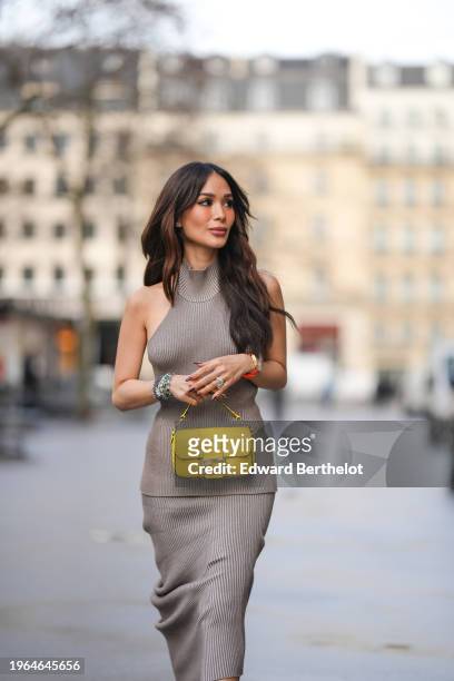 Heart Evangelista wears a sleeveless gray wool ribbed turtleneck long top, a matching midi skirt, the pair forming a long dress, bracelets, a yellow...