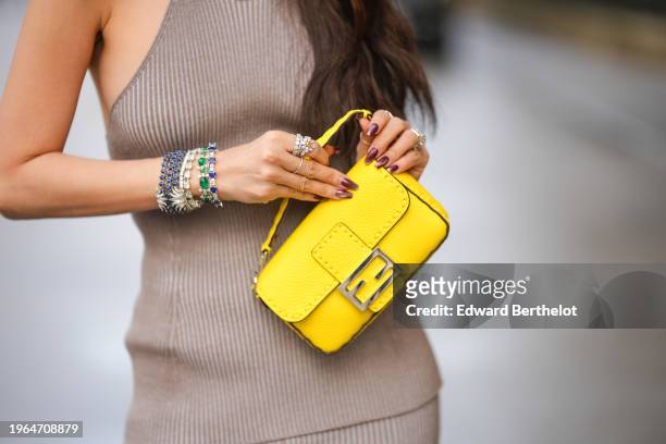 Heart Evangelista wears a yellow Fendi bag, jewelry, bejeweled bracelets, rings, purple nail polish and a gray ribbed dress, outside Fendi during the...