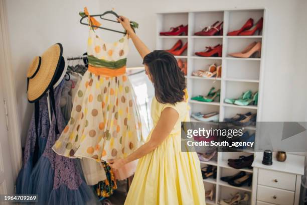 classy woman choosing dress for today - yellow retro dress stock pictures, royalty-free photos & images