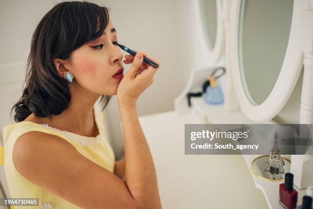 classy woman applying make up - eye liner stock-fotos und bilder