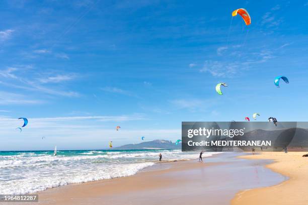 tarifa beach in cadiz surf city skyline of andalusia spain with lots of kitesurfing kites - tarifa stock pictures, royalty-free photos & images