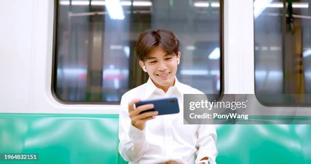 man watch video with earbuds - mrt train stock pictures, royalty-free photos & images