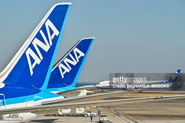 This photo taken on January 30, 2024 shows a passenger plane from Japan's All Nippon Airways taxiing past others parked at the gates at Tokyo...