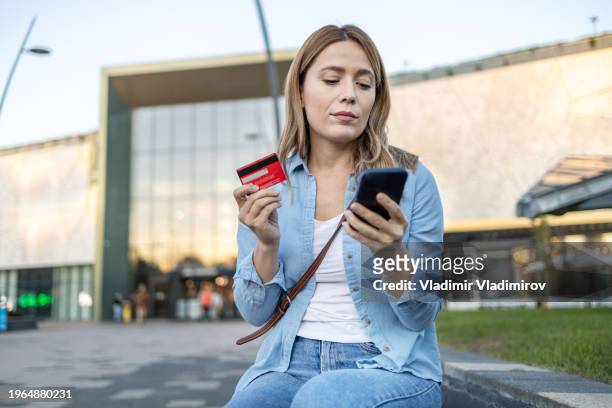 woman making an reservation outside with smart phone and credit card - click and collect stock pictures, royalty-free photos & images