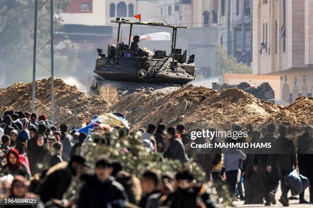 An Israeli battle tank is deployed to guard a position as displaced Palestinians flee from Khan Yunis in the southern Gaza Strip on January 30 amid...