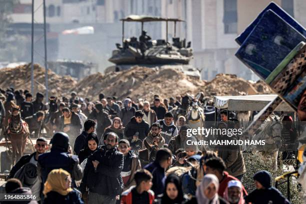 An Israeli battle tank is deployed to guard a position as displaced Palestinians flee from Khan Yunis in the southern Gaza Strip on January 30 amid...