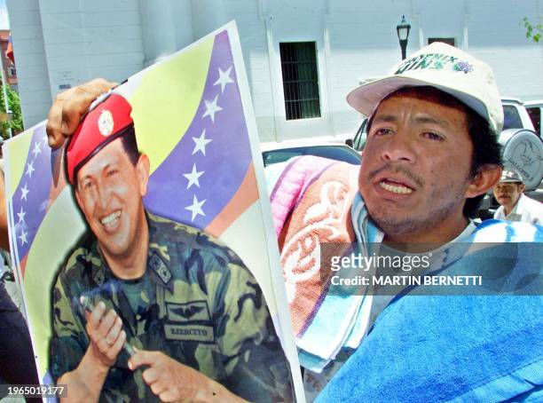 Vendor is seen holding a poster of president Hugo Chavez dressed in military uniform, in Caracas, 17 April 2002. Un comerciante vende afiches del...