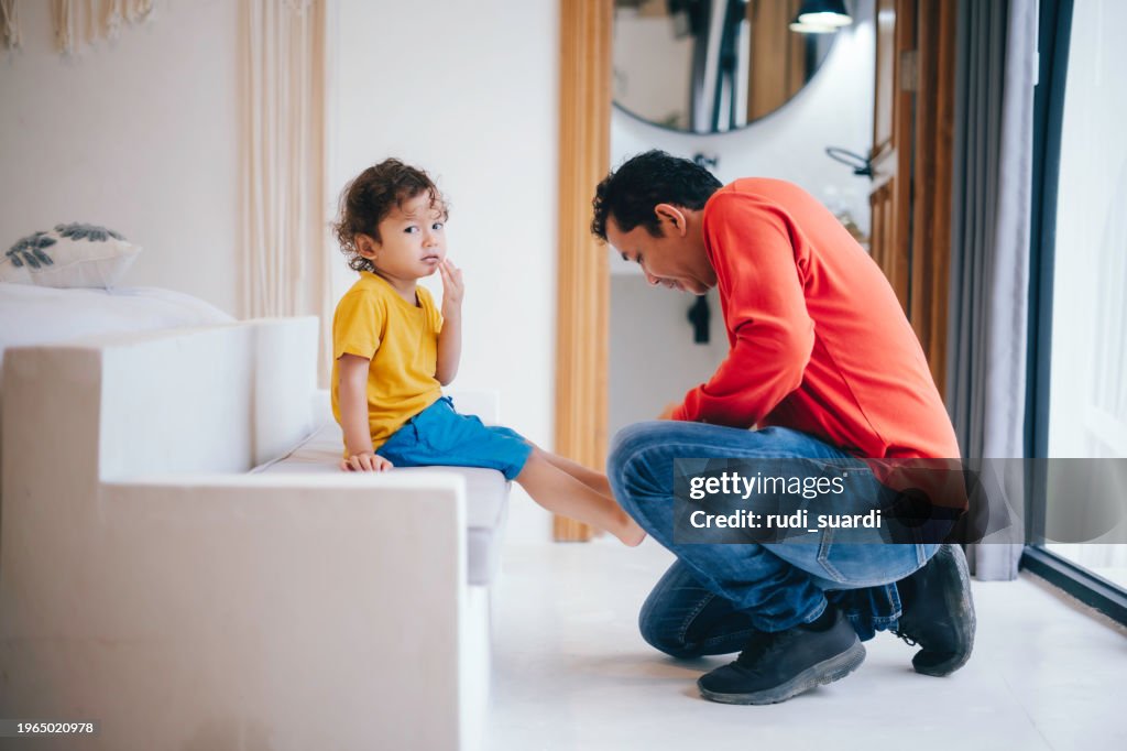 Father helping his son put his shoes on