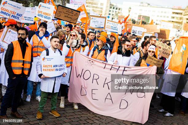 January 2024, Lower Saxony, Hanover: People take part in a demonstration by university hospital doctors on Opernplatz. One banner reads "The Working...